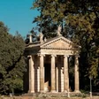 A columned neoclassical facade with statues, framed by trees