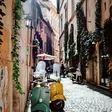 Scooters parked along a narrow cobblestone street in Rome